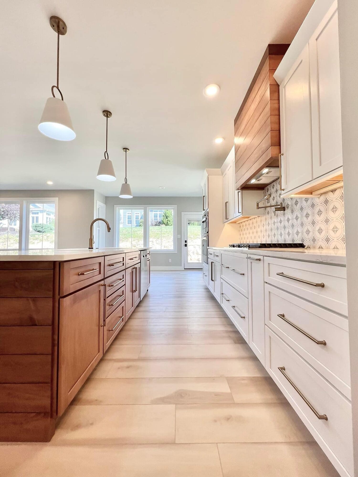 Galley-style kitchen with white perimeter cabinetry, a stained wood island, patterned tile backsplash, and wood plank flooring.